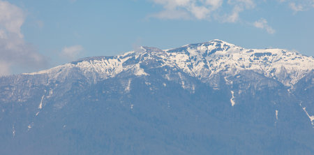 A mountain range covered in snow. The sky is blue and clear. The mountains are majestic and...