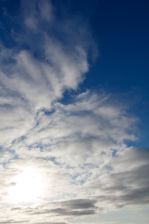 The sky is blue with a few clouds scattered throughout. The sun is shining brightly, creating a beautiful contrast with the cloudy skyの写真素材