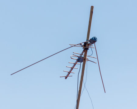 A tall antenna is on a pole. The pole is brown and the antenna is blue. The sky is clear and blueの写真素材