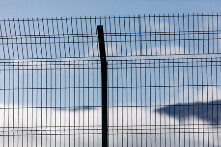 A fence with a metal pole sticking out of it. The sky is blue and clearの写真素材