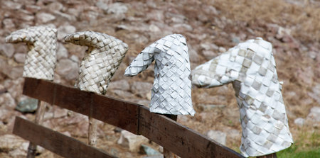 Three white and black hats are on a wooden fence. The hats are made of paper and are arranged in a row. Scene is calm and peaceful, as the hats are not moving and are simply sitting on the fenceの写真素材