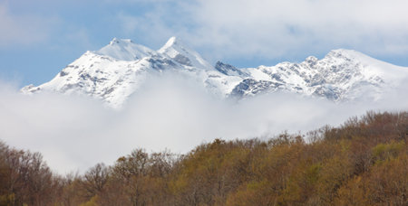 A mountain range covered in snow and clouds. The clouds are white and fluffy, and the mountains are tall and majestic. The scene is peaceful and sereneの写真素材