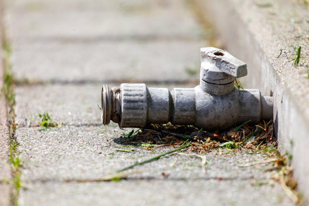 A rusty pipe is laying on the ground. The pipe is old and has a broken cap. The image has a mood of neglect and decayの写真素材