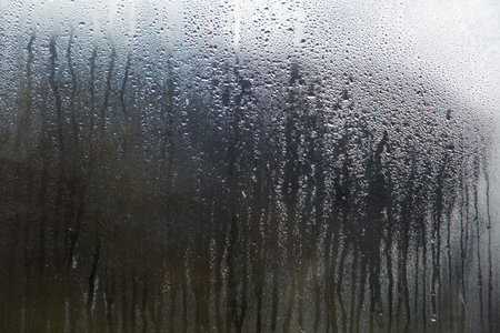 The window is foggy and has water droplets on it. Scene is gloomy and dampの写真素材