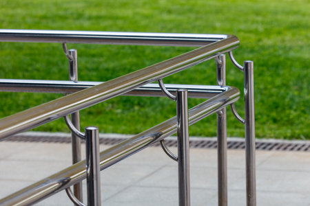 A metal railing with a green grassy background. The railing is silver and has a modern lookの写真素材
