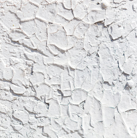 The wall is covered in cracks and peeling paint, giving it a worn and aged appearance. The texture of the wall is rough and uneven, with some areas appearing to be crumbling. Scene is one of decayの写真素材