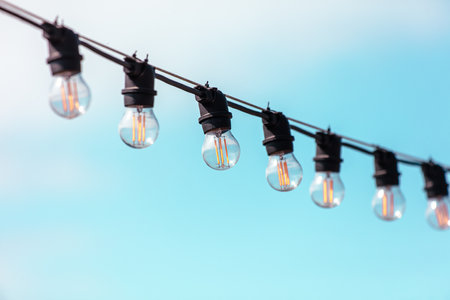 A string of lights with bulbs that are lit up. The lights are hanging from a wire and are all the same colorの写真素材