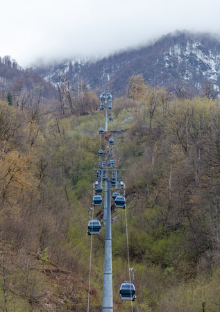 A long cable with many cable cars on it. The cable cars are going up a mountainの写真素材