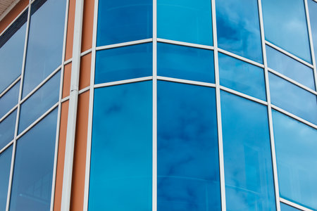 A building with blue glass windows and a brown trim. The blue glass is reflective and the building is tallの写真素材