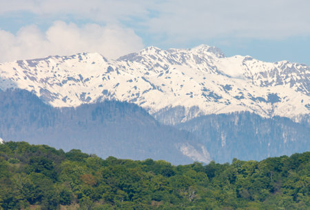 The mountains are covered in a thick layer of snow, and the sky is overcast with clouds. The scene is calm and tranquil, with the mountains towering over the landscapeの写真素材