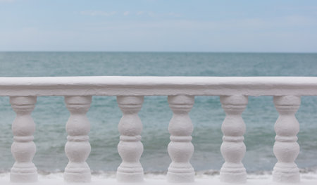 A white railing overlooking the ocean. The railing is empty and the ocean is calmの写真素材