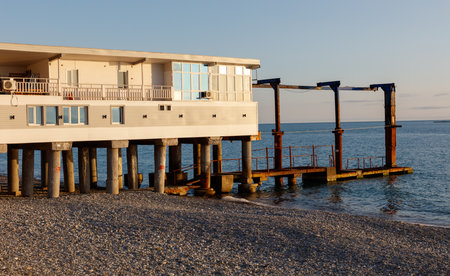 A pier with a building on it and a dock. The building is white and the dock is rustyの写真素材
