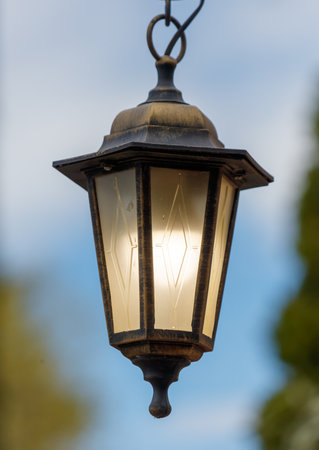 A lamp with a light shining on it is hanging from a hook. The light is on, illuminating the area around the lampの写真素材