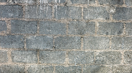 A brick wall with a gray color. The wall is made of bricks and has a rough textureの写真素材