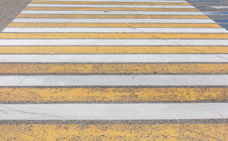 A yellow and white striped road with a white line. The stripes are faded and the road is crackedの写真素材