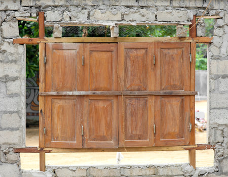 A window with wooden shutters is open, revealing a brick wall. The shutters are old and worn, giving the scene a sense of history and nostalgiaの写真素材