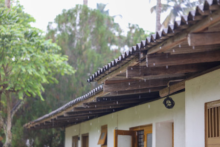 The roof of a building is covered in rain, and the rain is falling in a steady streamの写真素材
