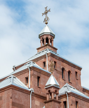 A church steeple with a cross on top. The cross is gold and silver. The sky is blue and there are cloudsの写真素材