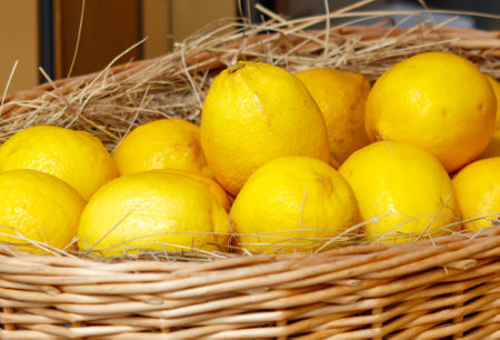 A basket full of lemons. The lemons are yellow and are in a woven basketの写真素材