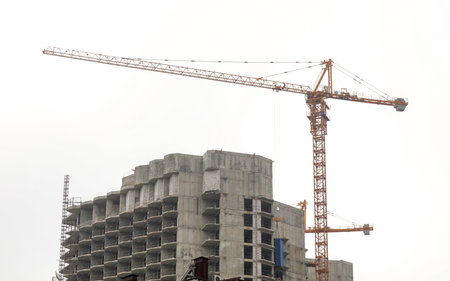 A crane is lifting a building. The crane is yellow and is in the middle of the buildingの写真素材