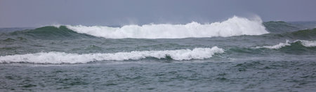 The ocean is calm and the waves are small. The sky is cloudy and the water is a deep blue colorの写真素材