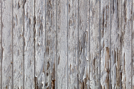 A wooden surface with white paint peeling off. The surface is rough and uneven, giving it a rustic and aged appearanceの写真素材