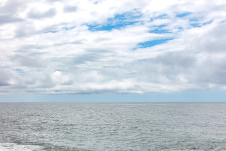The sky is cloudy and the ocean is calm. The clouds are scattered and the sky is mostly blueの写真素材