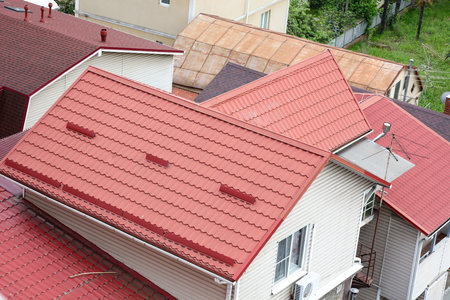 A red roof with a white trim sits atop a white house. The roof is slanted and has a red trimの写真素材