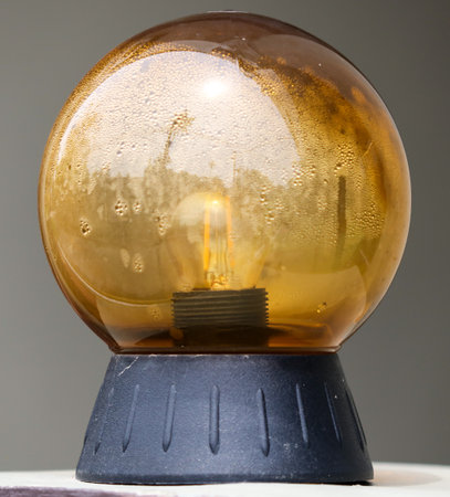 A glass egg shaped lamp with a light inside. The lamp is sitting on a black baseの写真素材