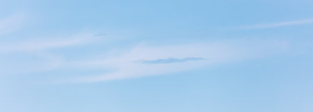 A blue sky with a cloud in the middle. The sky is clear and bright. The cloud is small and whiteの写真素材