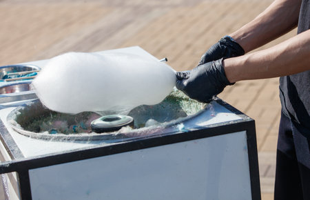 A person is making cotton candy. The cotton candy is in a bowl and the person is using a spatula to make itの写真素材