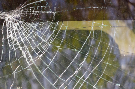 A spider web is shown with a reflection of a person in the background. The spider web is torn and the reflection is blurry. Scene is somewhat eerie and unsettlingの写真素材