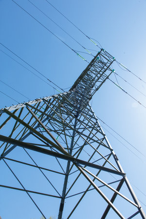 A tall power tower with wires and a blue sky in the background. The tower is tall and has a lot of wires coming out of itの写真素材