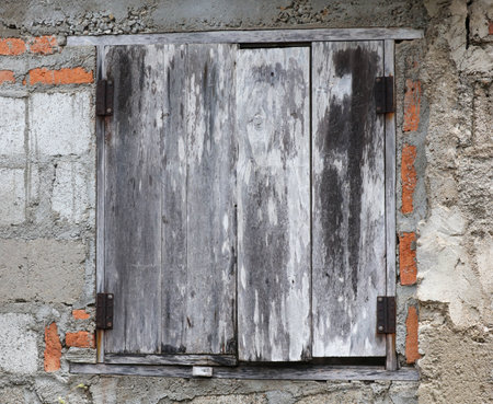 A window with a wooden frame and a brick wall. The window is open and the frame is old and wornの写真素材