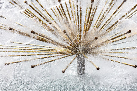 A fountain with a structure in the middle of it. The structure is made of bamboo sticks. The water is spraying out of the structureの写真素材
