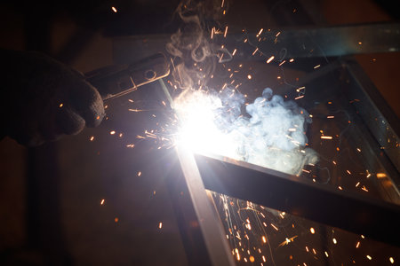 A person is welding metal with a torch. Concept of danger and risk, as the sparks and heat from the...