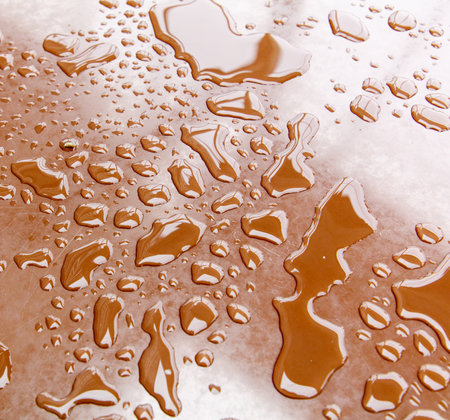 A brown surface with many small drops of water on it. The drops are scattered all over the surface, creating a sense of movement and energy. Scene is one of fluidity and motionの写真素材