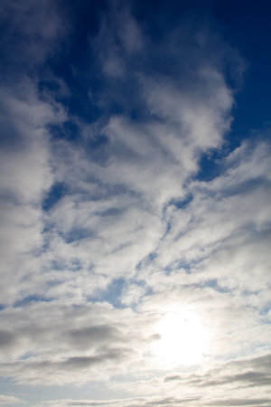 The sky is blue with a few clouds scattered throughout. The sun is shining brightly, creating a warm and inviting atmosphereの写真素材