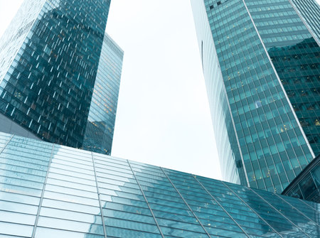 A city skyline with three tall buildings, all of which are made of glass. The buildings are very tall and are located in a city. The sky is cloudyの写真素材