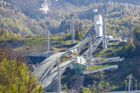 A ski slope with a large white building in the background. The building is surrounded by trees and has a flag on topの写真素材