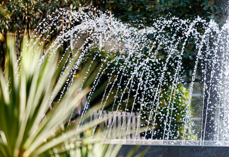A fountain with a person in the background. The water is white and is spraying out of the fountainの写真素材