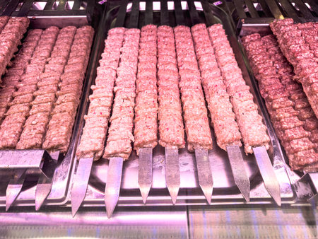 A tray of meat skewers is displayed in a restaurant. The skewers are pink and appear to be cookedの写真素材