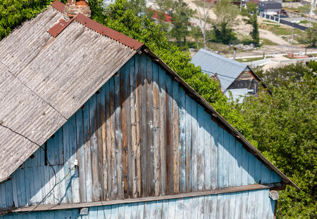 A blue house with a wooden roof and a chimney. The roof is old and has a lot of rustの写真素材