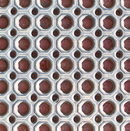 A pattern of holes in a metal surface. The holes are evenly spaced and the metal is silver