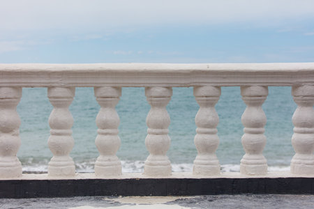 A white railing overlooking the ocean. The railing is empty and the ocean is calmの写真素材