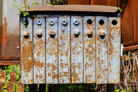 A rusted mailbox with a green plant growing out of it. The mailbox has a lot of holes and is in a state of disrepairの写真素材