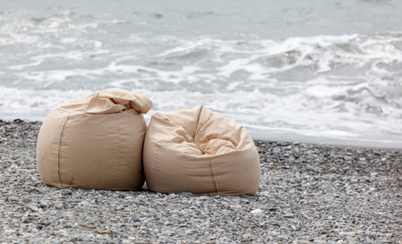 Two tan beach chairs are laying on the beach. The chairs are empty and the beach is calmの写真素材
