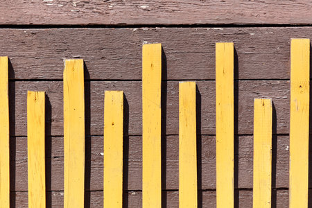 The yellow and brown wooden fence has a striped pattern. The yellow stripes are on the top of the brown woodの写真素材