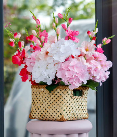 A beautiful arrangement of pink and white flowers is displayed in a basket on a pink stool. The flowers are arranged in a way that creates a sense of harmony and balance, with the pinkの写真素材