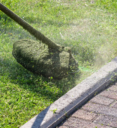 A lawn mower is cutting the grass on a lawn. The grass is cut to a short length, and the mower is leaving a pile of grass clippings on the ground. The scene is peaceful and calmの写真素材